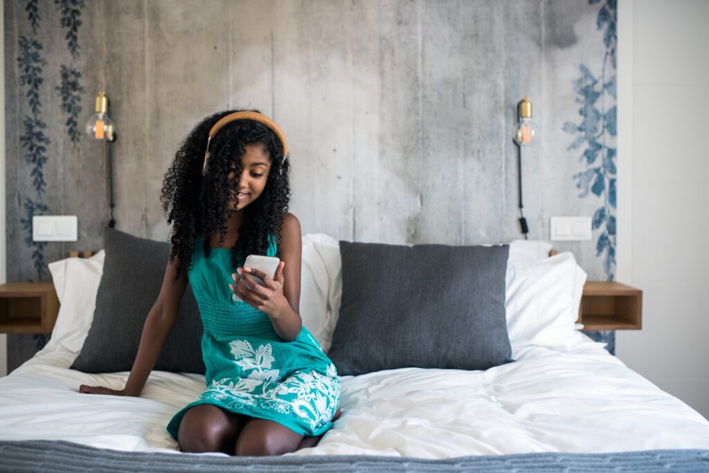 Black girl with headphones on bed